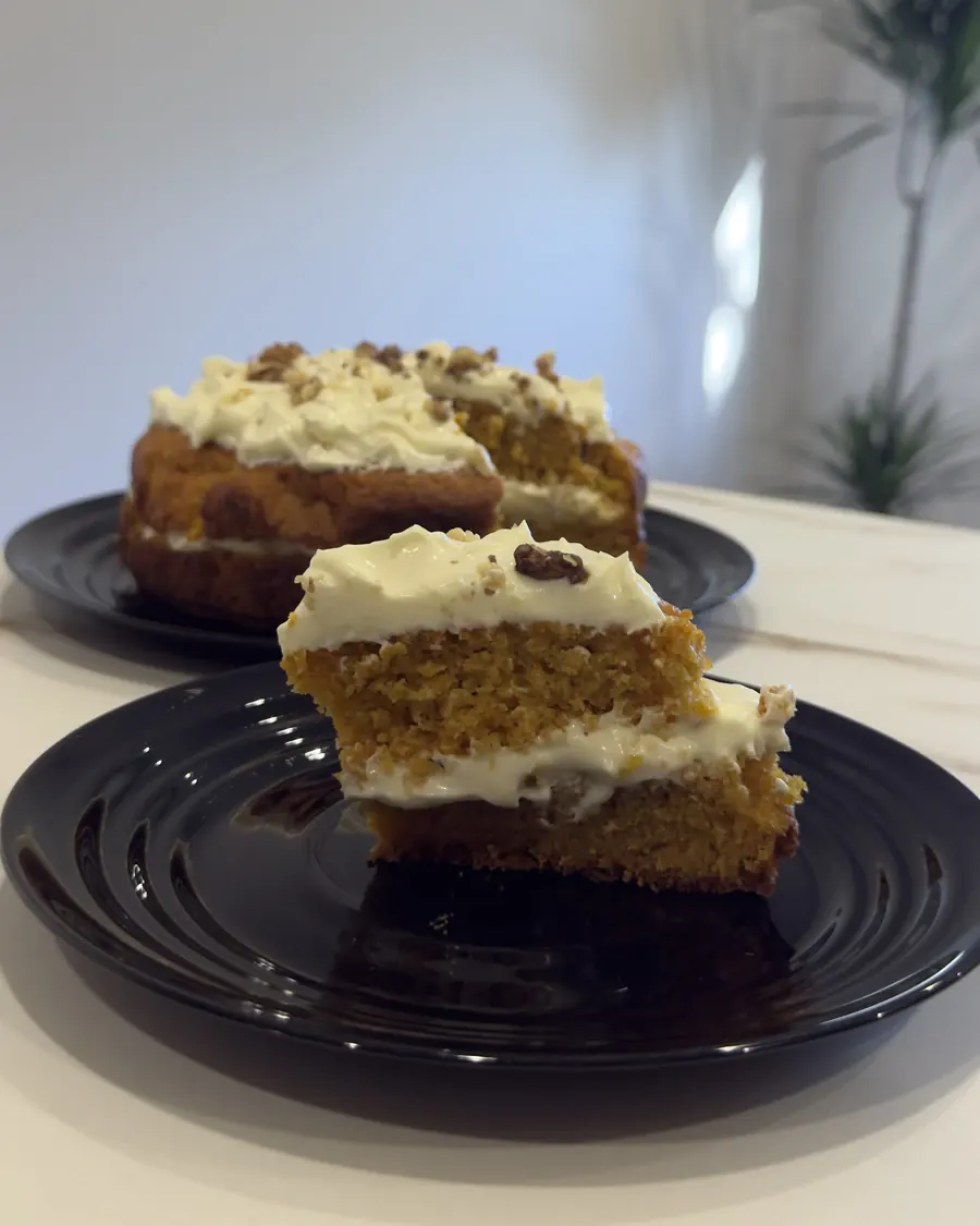 Porción de carrot cake de cerca, con dos capas de bizcocho especiado y crema de queso.