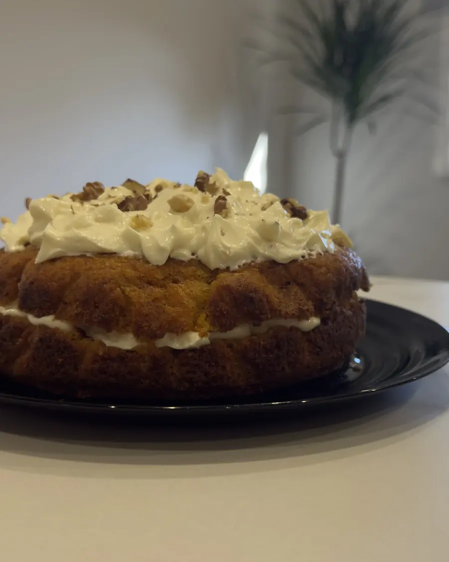 Carrot cake entera de perfil, con la crema de queso entre las dos capas de bizcocho.