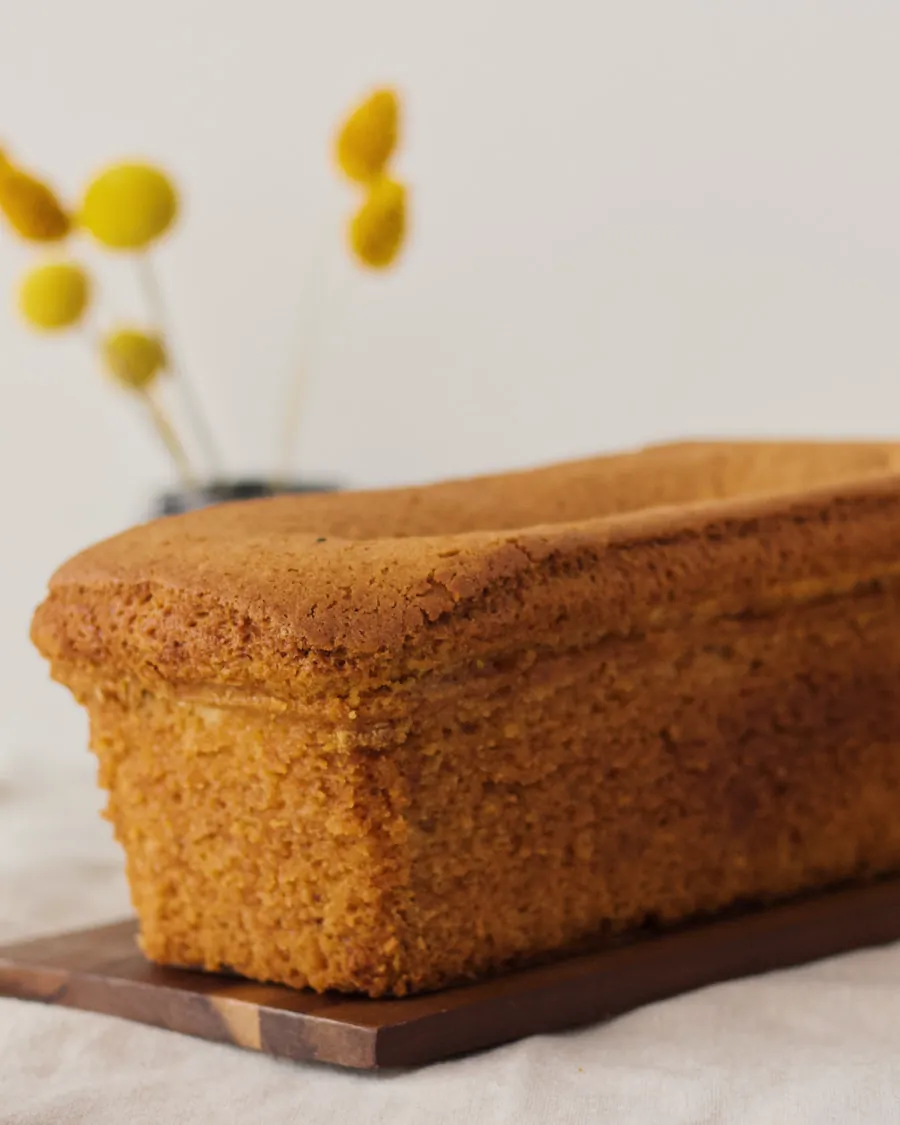 Torta boba entera, un bizcocho jugoso de corteza dorada, sobre una tabla de madera.