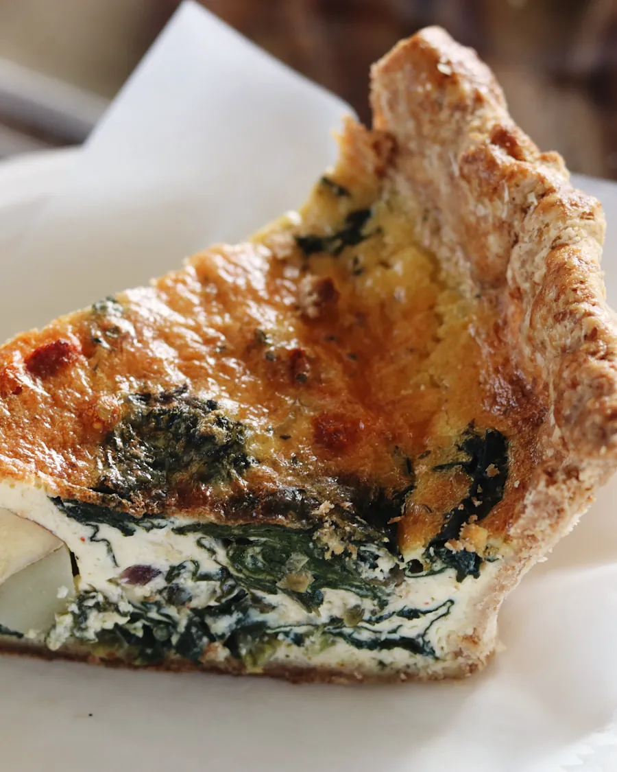 Porción de torta salada con relleno de verdura y queso, sobre papel de horno.